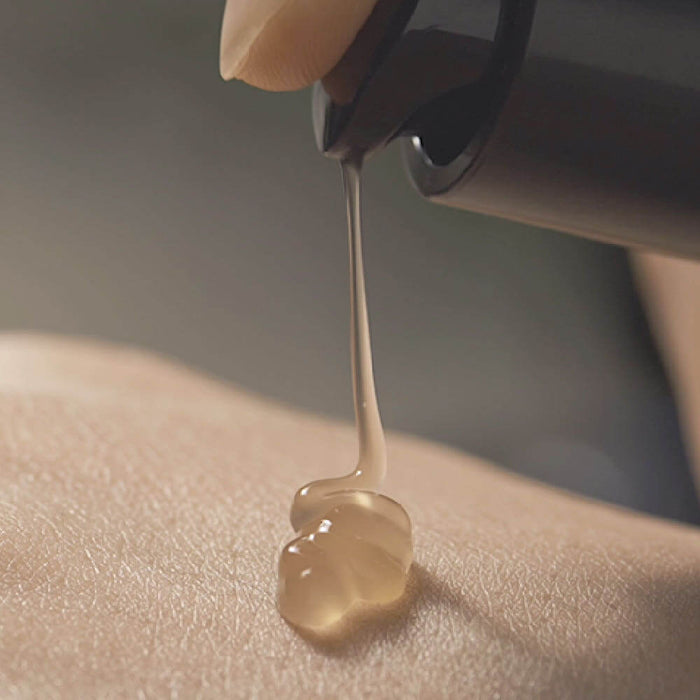 Close-up of PYUNKANG YUL Black Tea Boosting Serum 45ml being dispensed onto skin.