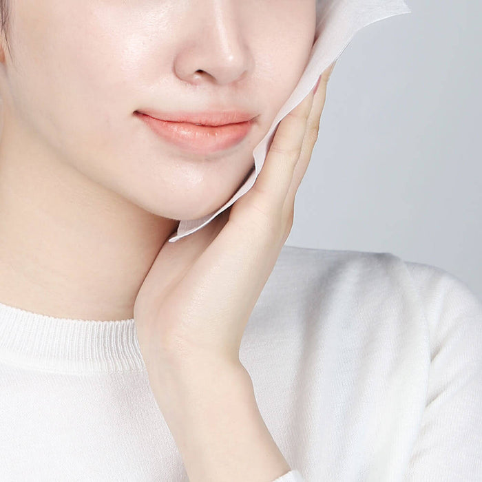 Woman using PYUNKANG YUL Calming Face Towels 80 Pieces on her face for a soft and calm skin care experience.