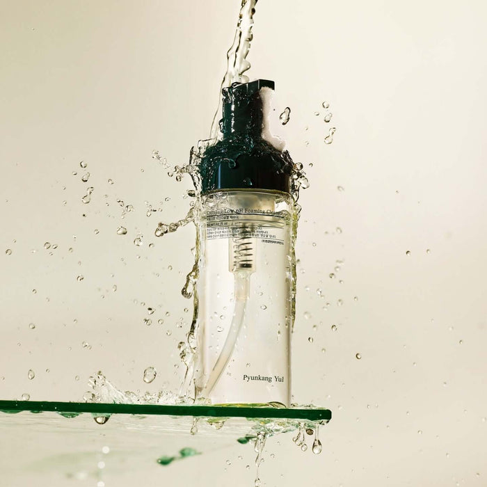 PYUNKANG YUL Calming Low pH Foaming Cleanser 150ml bottle with splashing water, showcasing refreshing skincare product.