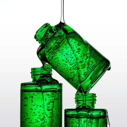 Three green glass bottles of PYUNKANG YUL Ultimate Soothing Solution Ampoule 30ml with liquid pouring from one to another against a white background.