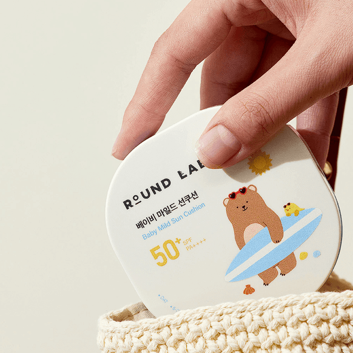 ROUND LAB Baby Mild Sun Cushion 16g in hand, SPF 50 packaging design with bear and chick illustration, eco-friendly skincare.