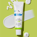 ROUND LAB Birch Juice Moisturizing Mild-Up Sunscreen 50ml on a green background with product swatches