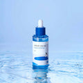 ROUND LAB Birch Moisture Ampoule 50ml bottle on water surface with blue backdrop.