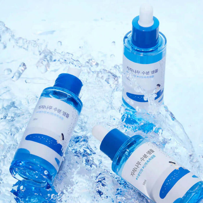Three bottles of ROUND LAB Birch Moisture Ampoule 50ml on a watery surface