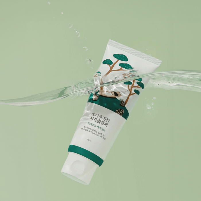 Bottle of ROUND LAB Pine Calming Cica Cleanser 150ml with water backdrop, highlighting soothing skincare properties.