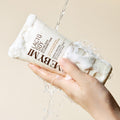 Hand holding SOME BY MI Lactosoy Enzyme Deep Cleansing Foam 100ml with water and bubbles, showcasing cleansing foam texture.