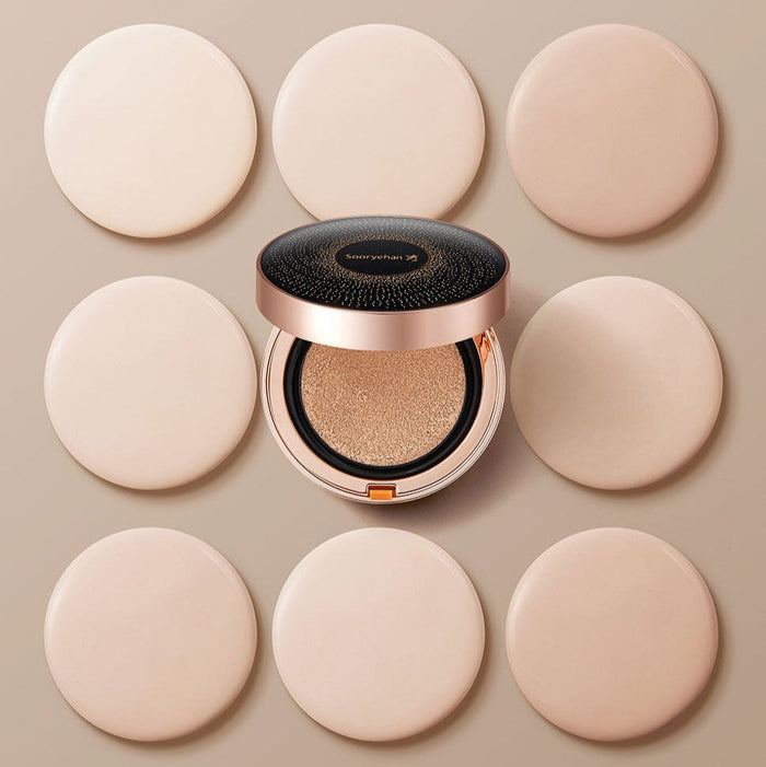 SOORYEHAN Beautiful Black Ginseng Cushion Project 15g surrounded by beige makeup pads, showcasing the elegant packaging and cushion texture.
