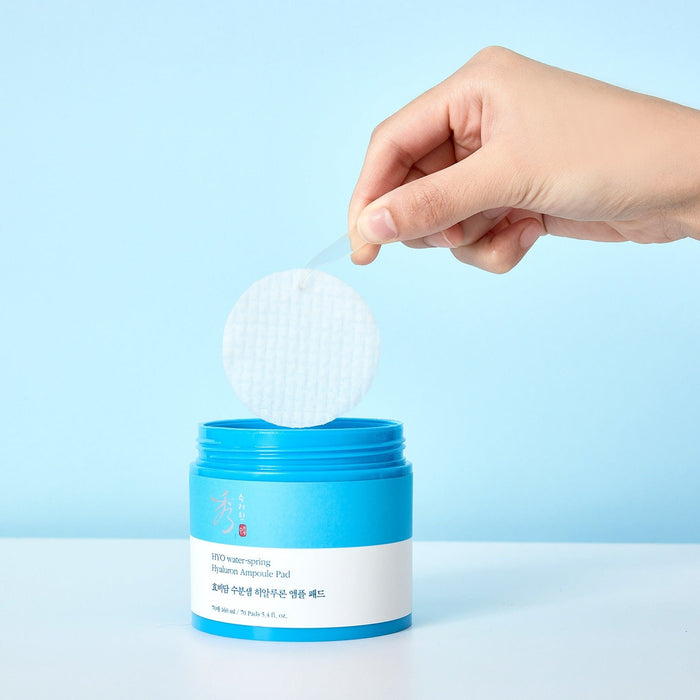 Hand holding a pad from SOORYEHAN Moiture Spring Hyaluronic Ampoule Pads 70 Sheets container