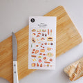 SUATELIER Food Trip #7 Stickers featuring diverse food designs on a wooden board with a knife. Perfect for planners and journals.