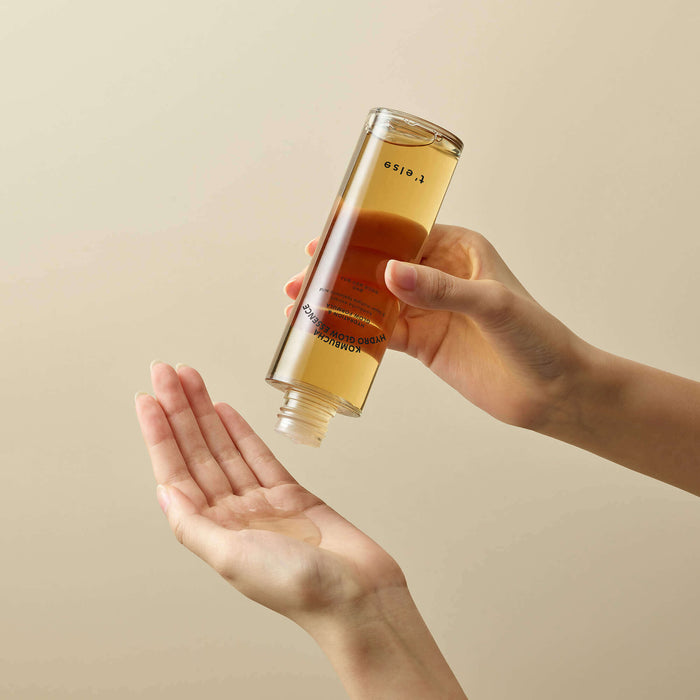 Hands using T'ELSE Kombucha Hydro Glow Essence 150ml for skincare routine