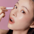 Woman applying TONY MOLY The Shocking Color Fixing Stick Shadow to eyelid with pink background.