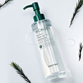 TONYMOLY Wonder Tea Tree Cleansing Oil 200ml bottle with green pump, surrounded by tea leaves on white background.