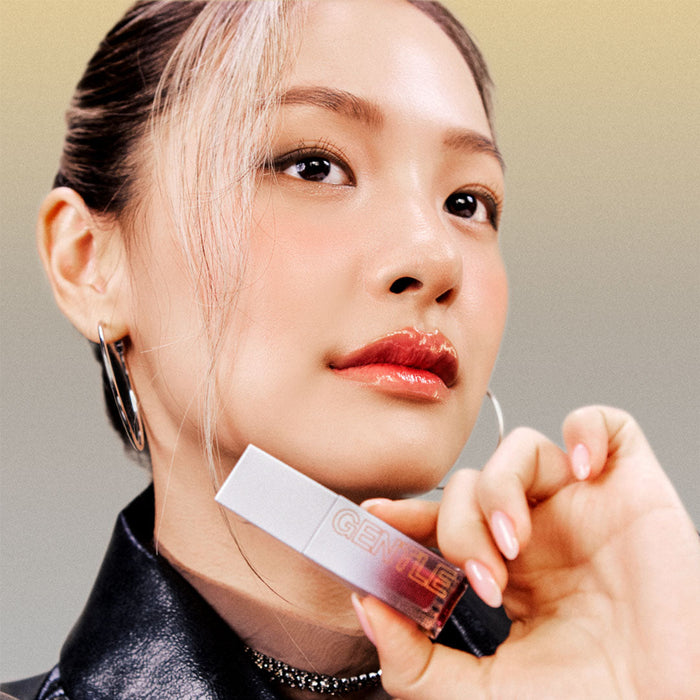 Model holding TOOQ Gentle Kiss Glow Tint with shimmering lip finish