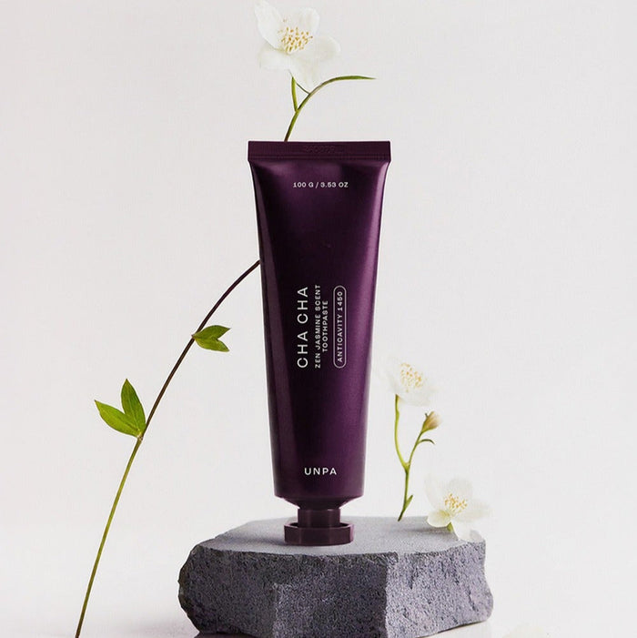 UNPA Cha CHa Zen Jasmine Scent 1450 High Fluoride Toothpaste 100g tube on rock with flowers