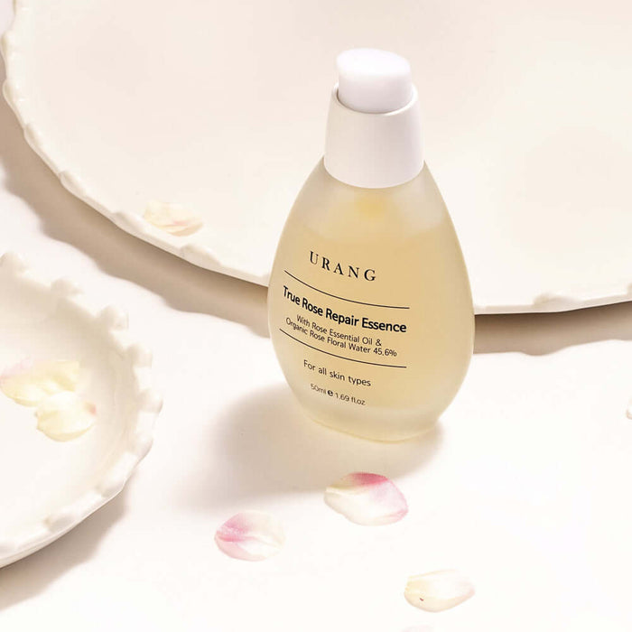 URANG True Rose Repair Essence bottle on white background with rose petals