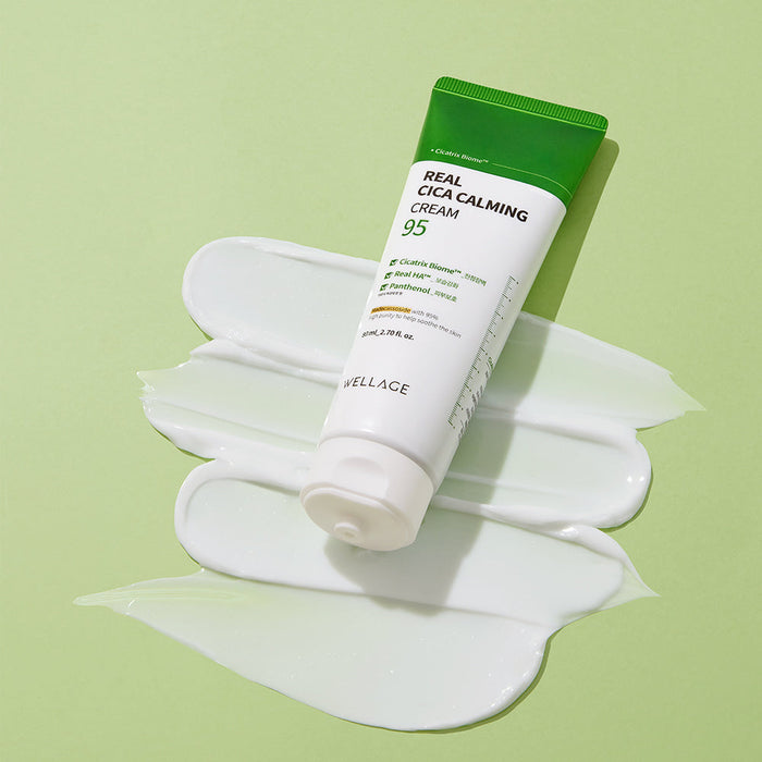 WELLAGE Real Cica Calming 95 Cream 80ml tube on a green background with a smear of cream
