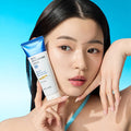 WELLAGE Real Hyaluronic 100 Cream 80ml held by model against blue background, showcasing skincare product.